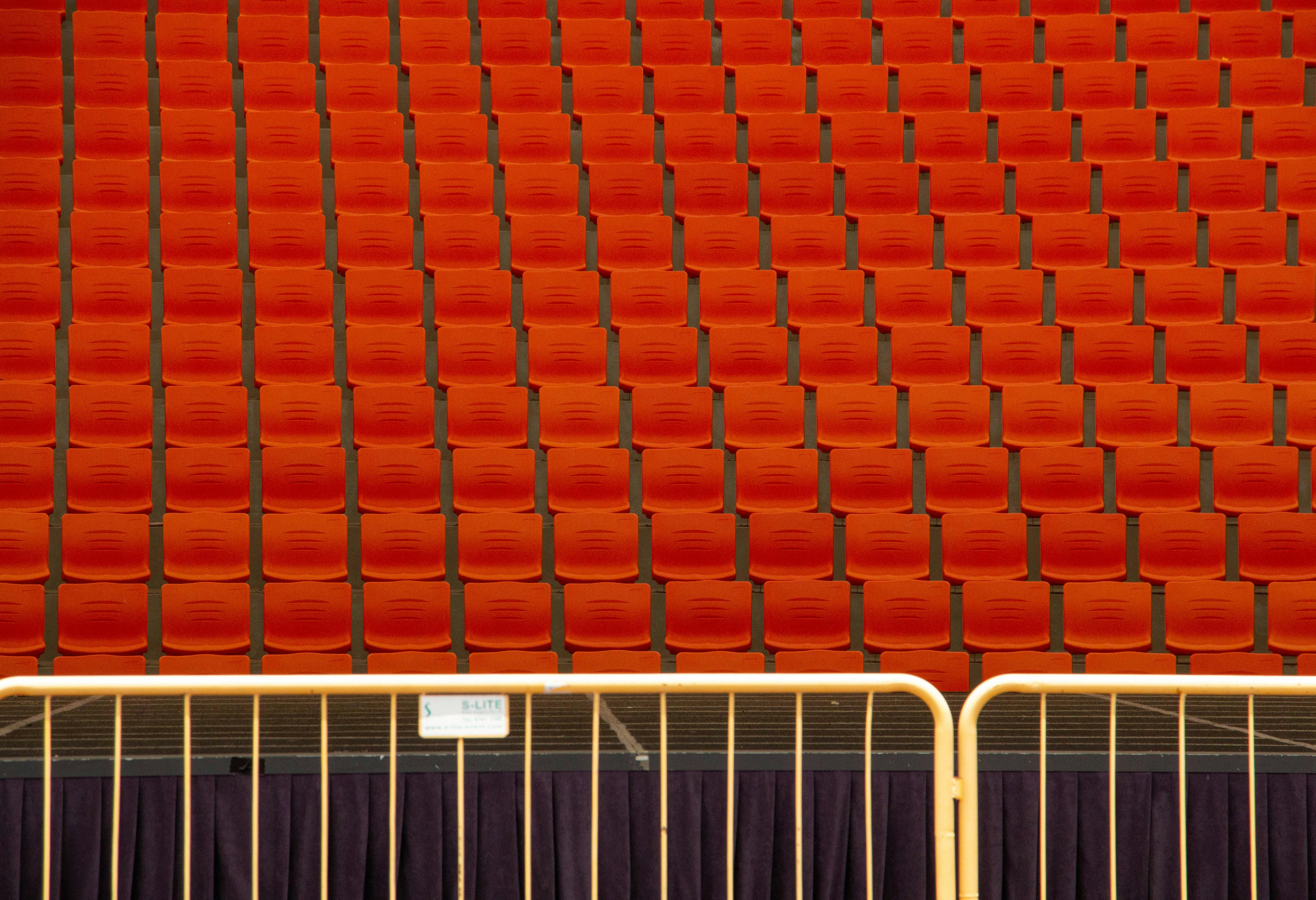 grátis Fileiras de assentos vermelhos no auditório com padrões repetitivos criam uma textura visual impressionante. Foto profissional