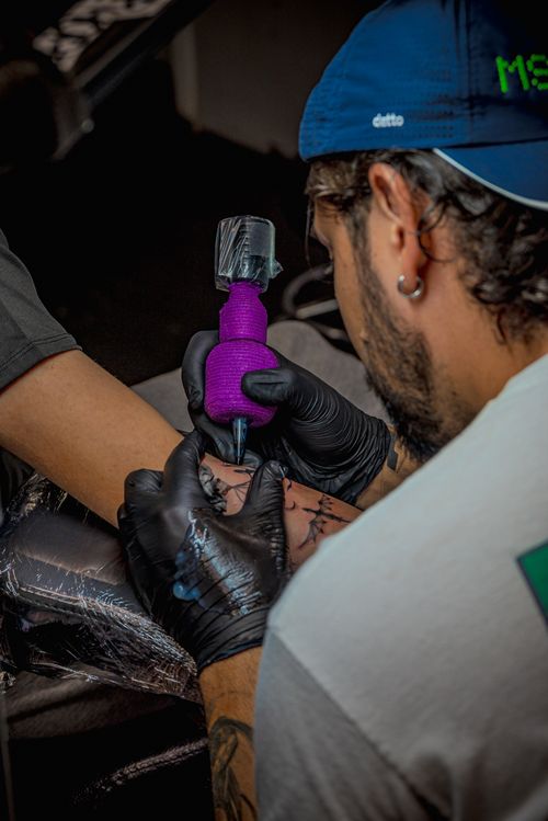 Free Skilled tattoo artist ink sketching an arm with precision and care in a studio. Stock Photo