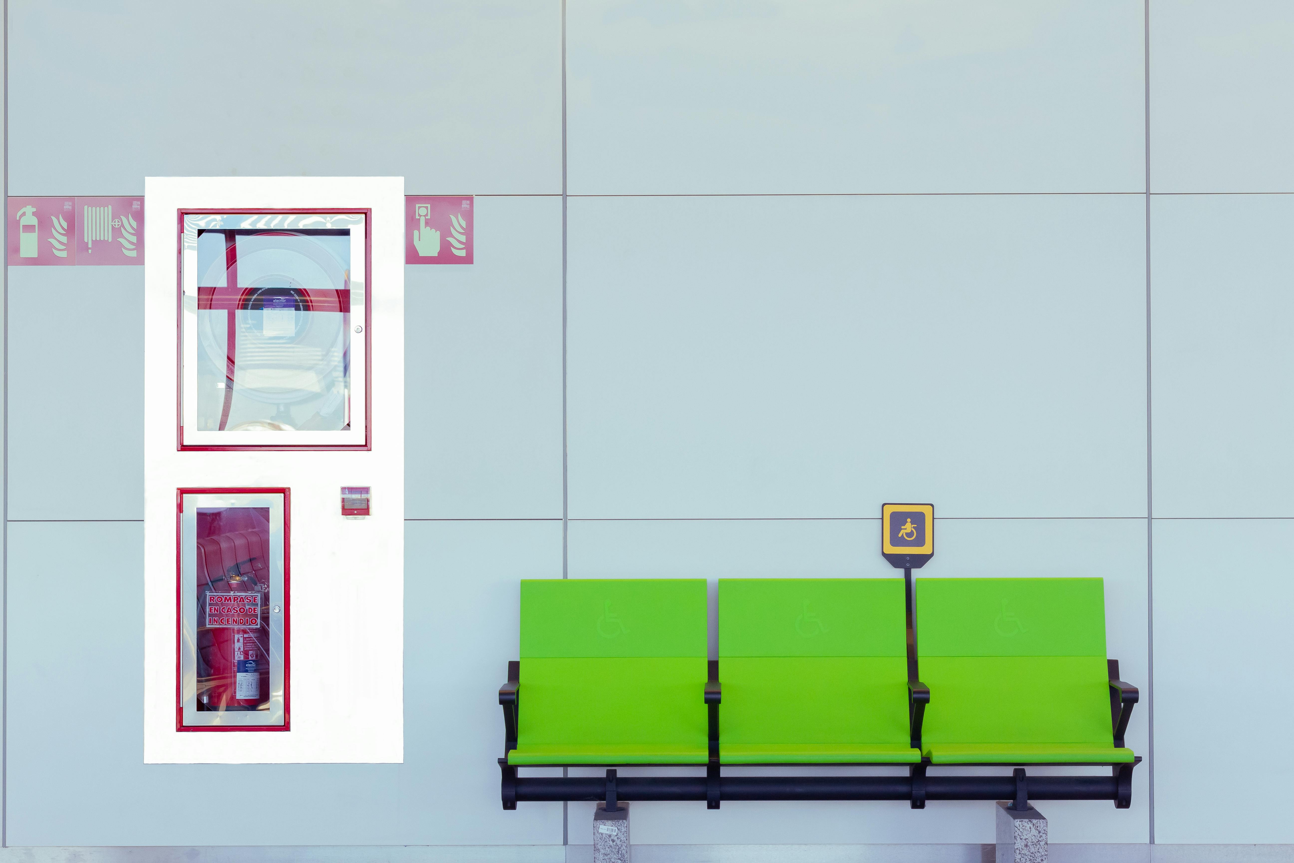 gratis Brandblusserkast naast de groene gehandicaptenzitplaats binnen. Stockfoto