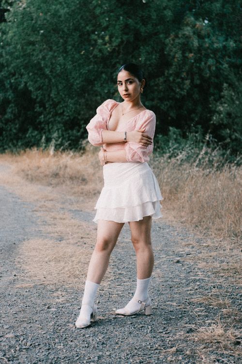 Free Woman in pink and white attire standing confidently on a countryside path, exuding elegance. Stock Photo