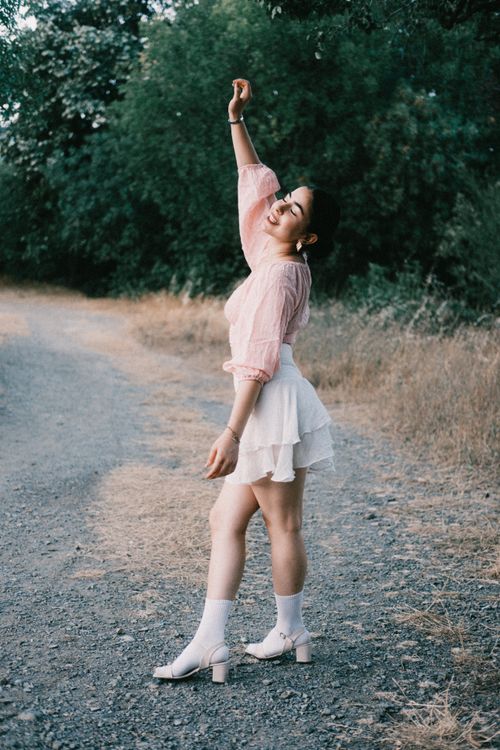 Free Carefree young woman dances on a rural path surrounded by greenery, enjoying the moment. Stock Photo