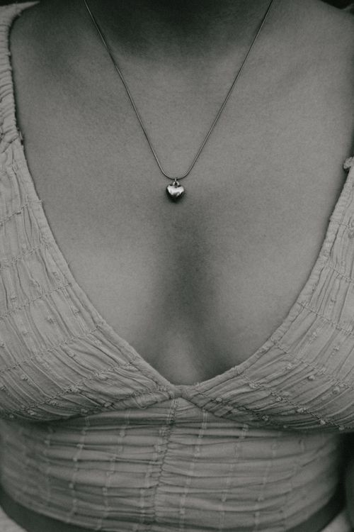 Free Close-up of a woman wearing a heart pendant necklace, emphasizing style and elegance. Stock Photo