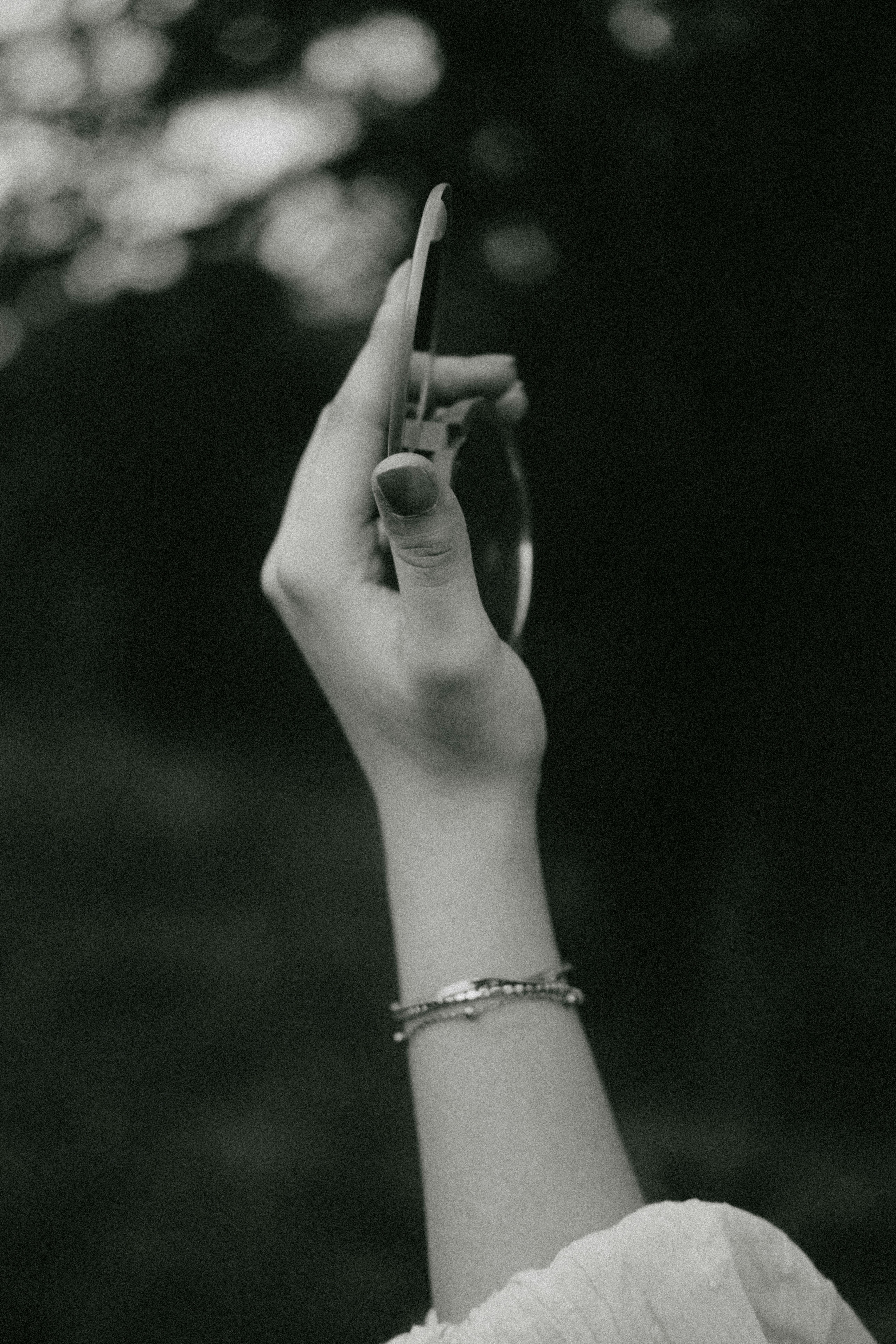 Gratis Bella foto in bianco e nero di una mano che regge uno specchio in un ambiente esterno. Foto a disposizione