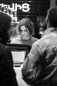 Customer interaction in a night cafe, captured in a classic black and white style.