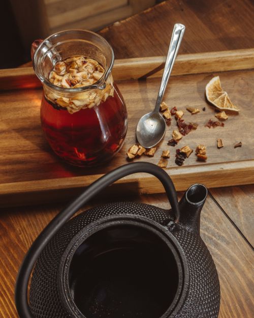 Free Rustic scene featuring a glass jug of herbal tea and a black teapot on a wooden tray. Stock Photo