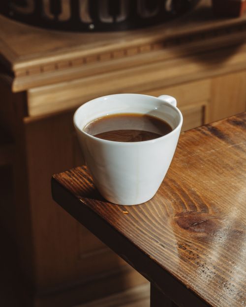Free A steaming cup of coffee on a rustic wooden table, exuding warmth and comfort. Stock Photo