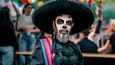 Man in Day of the Dead costume with face paint participating in a cultural celebration.