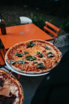 Delicious margherita pizza served on a rustic orange outdoor table. Perfect for a casual dining experience.