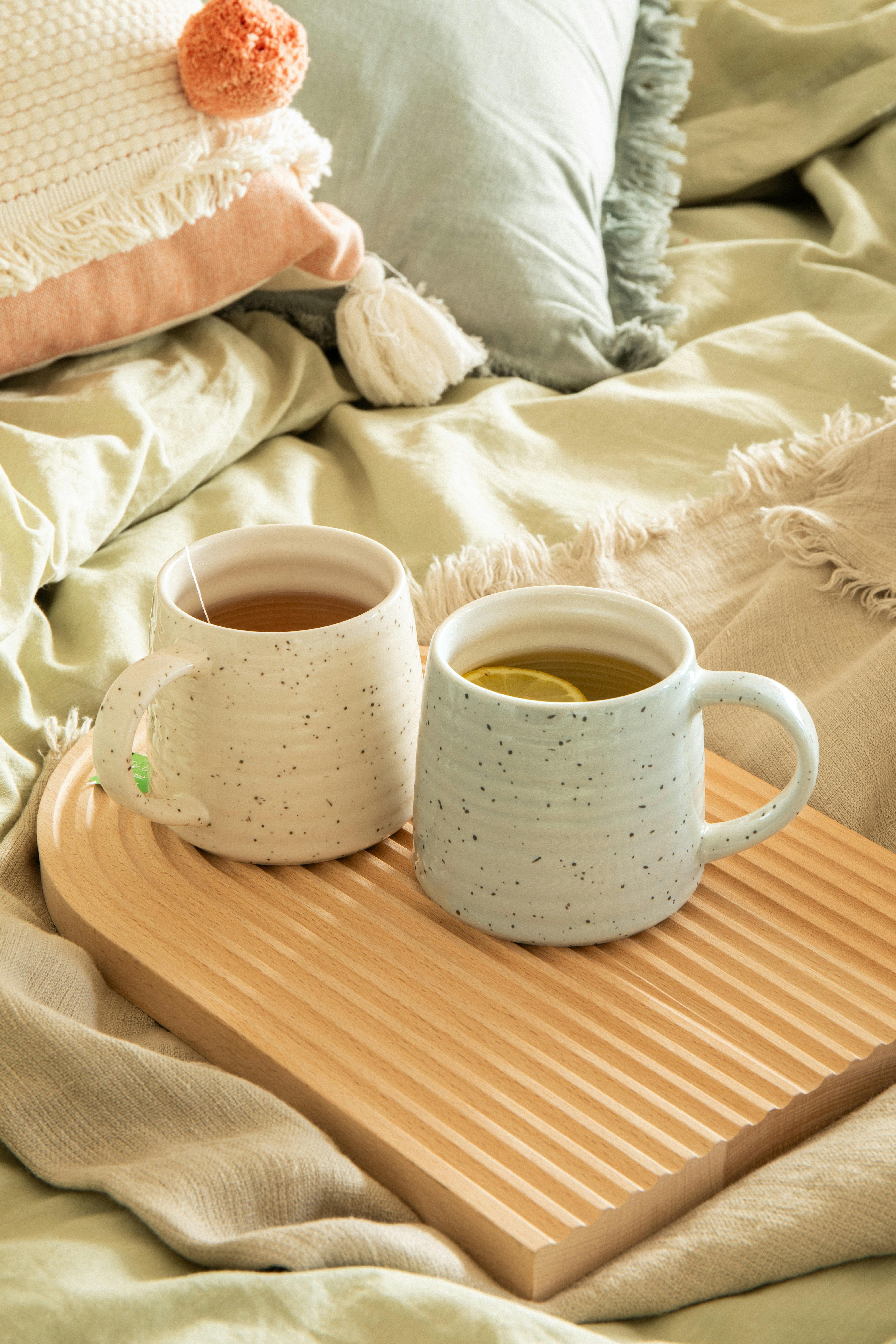 Two rustic mugs with herbal tea on a wooden tray in a cozy setting.