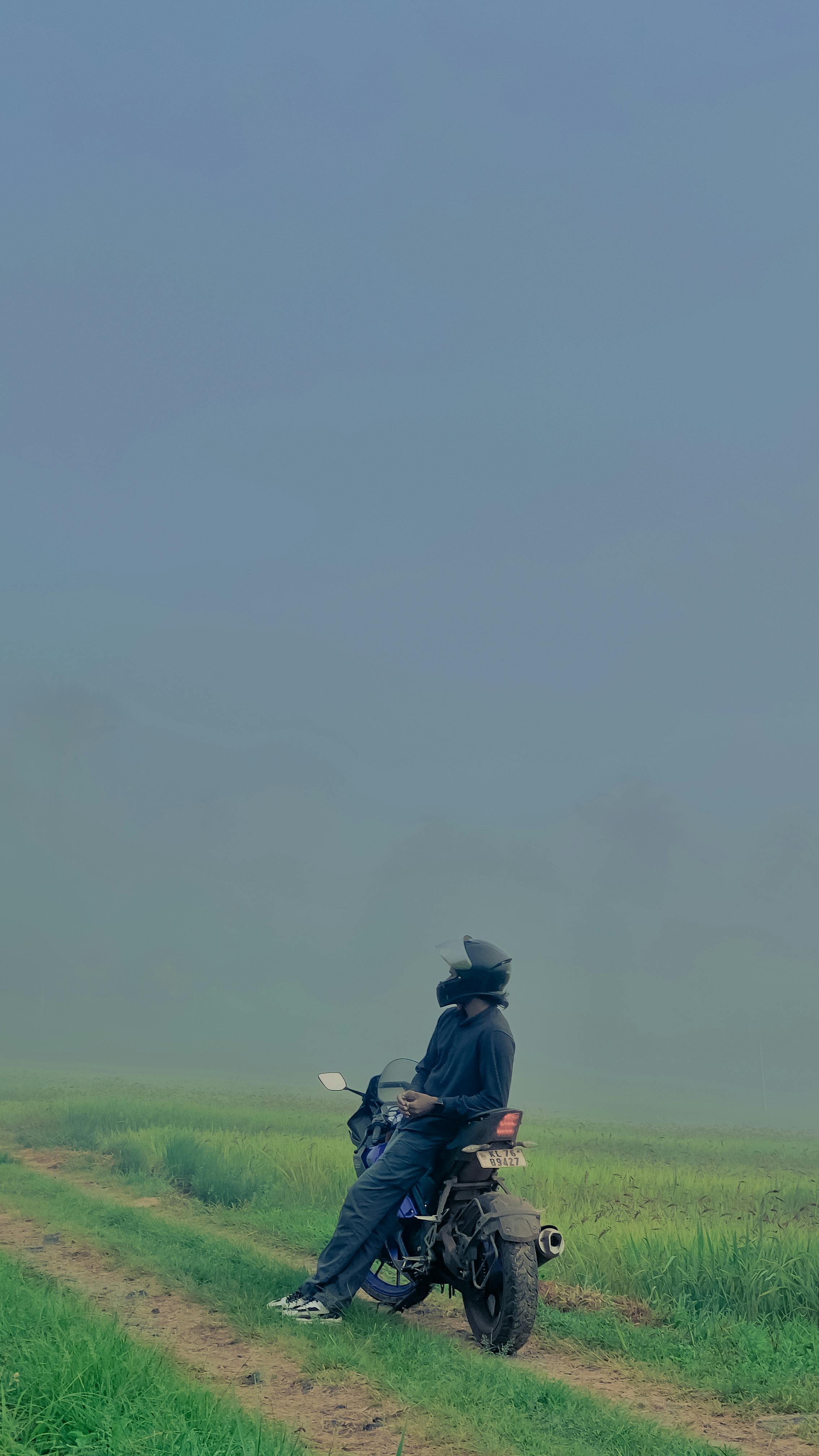 Solitary motorcyclist enjoys a misty trail ride through lush, green scenery in Wayanad, Kerala, India.