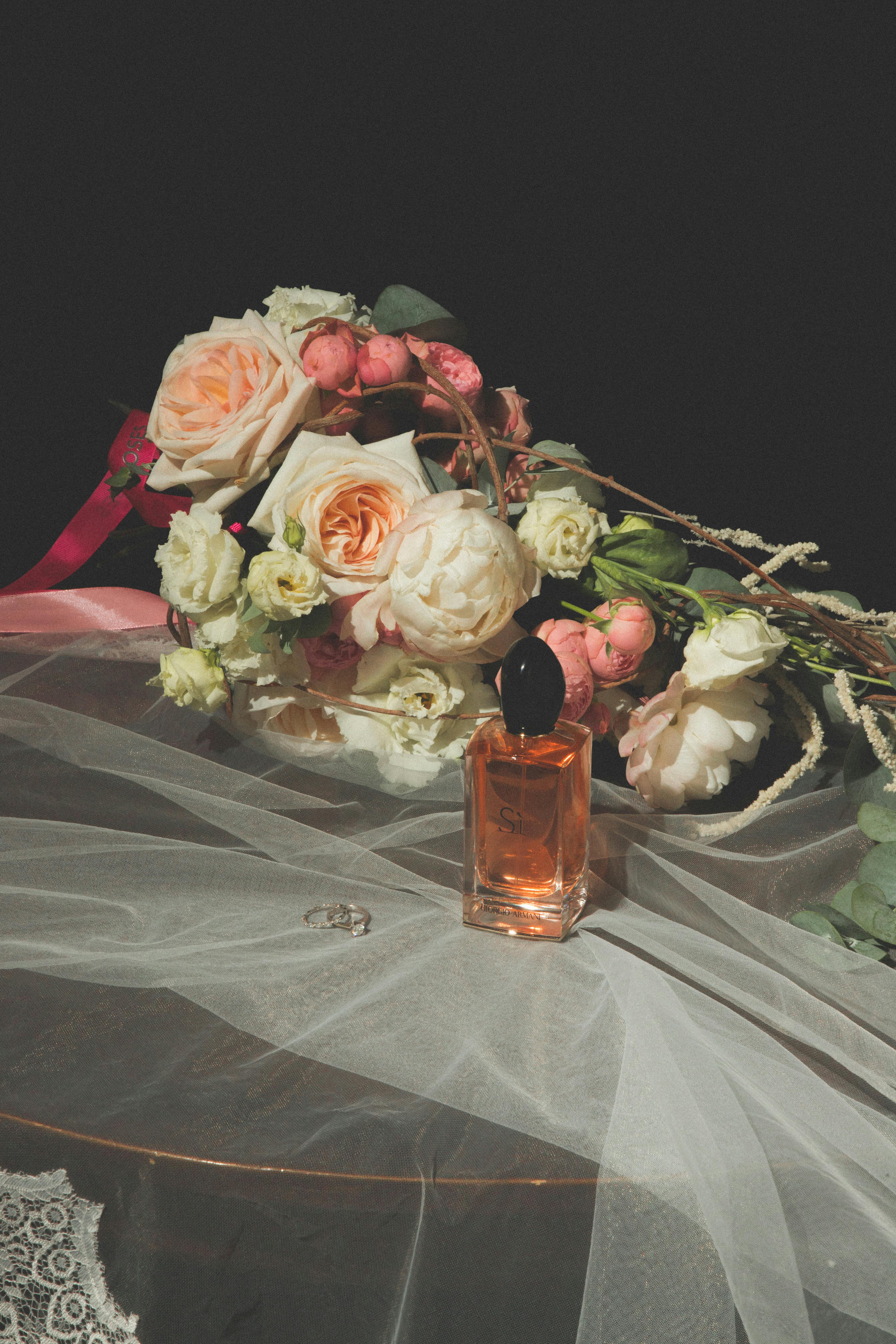 Perfume bottle with lush floral bouquet on delicate veil, evoking romance and elegance.