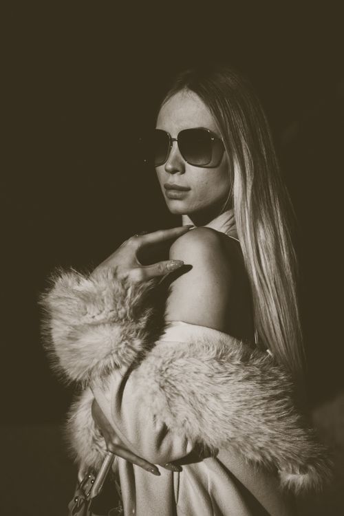 Free Stylish woman in fur coat and sunglasses posing confidently in a modern fashion portrait. Stock Photo