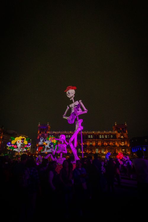 Free Vibrant festival scene with illuminated skeletons and colorful lights at night. Stock Photo