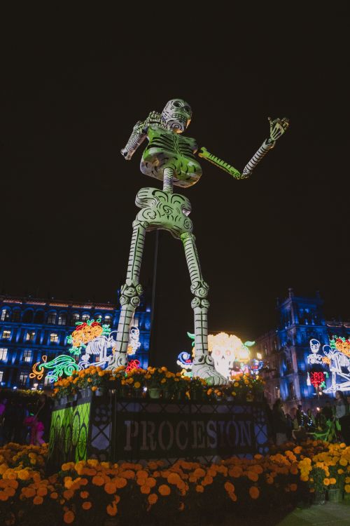 Free A giant skeleton sculpture illuminated during Day of the Dead celebrations, surrounded by vibrant lights. Stock Photo