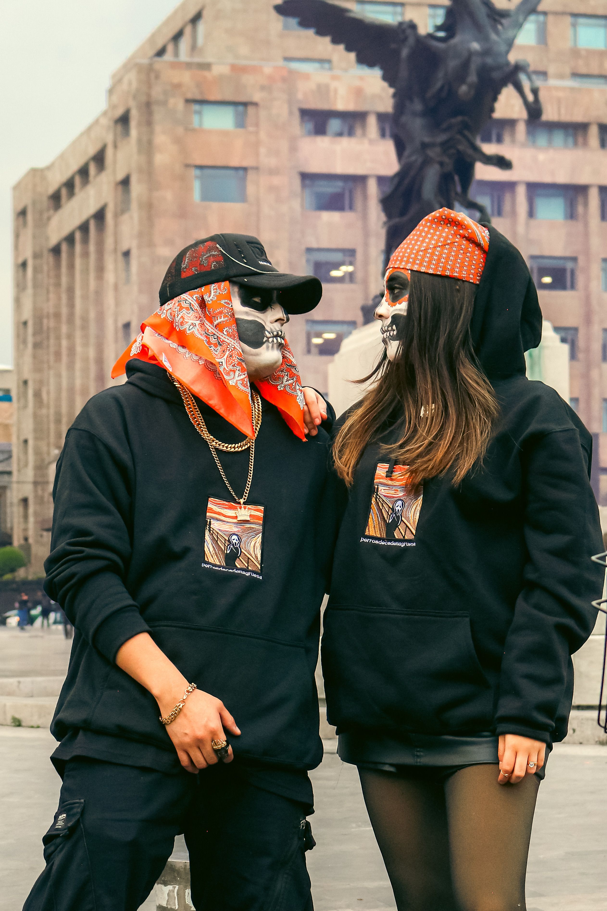 Two adults in skeleton makeup and hoodies in an urban setting.