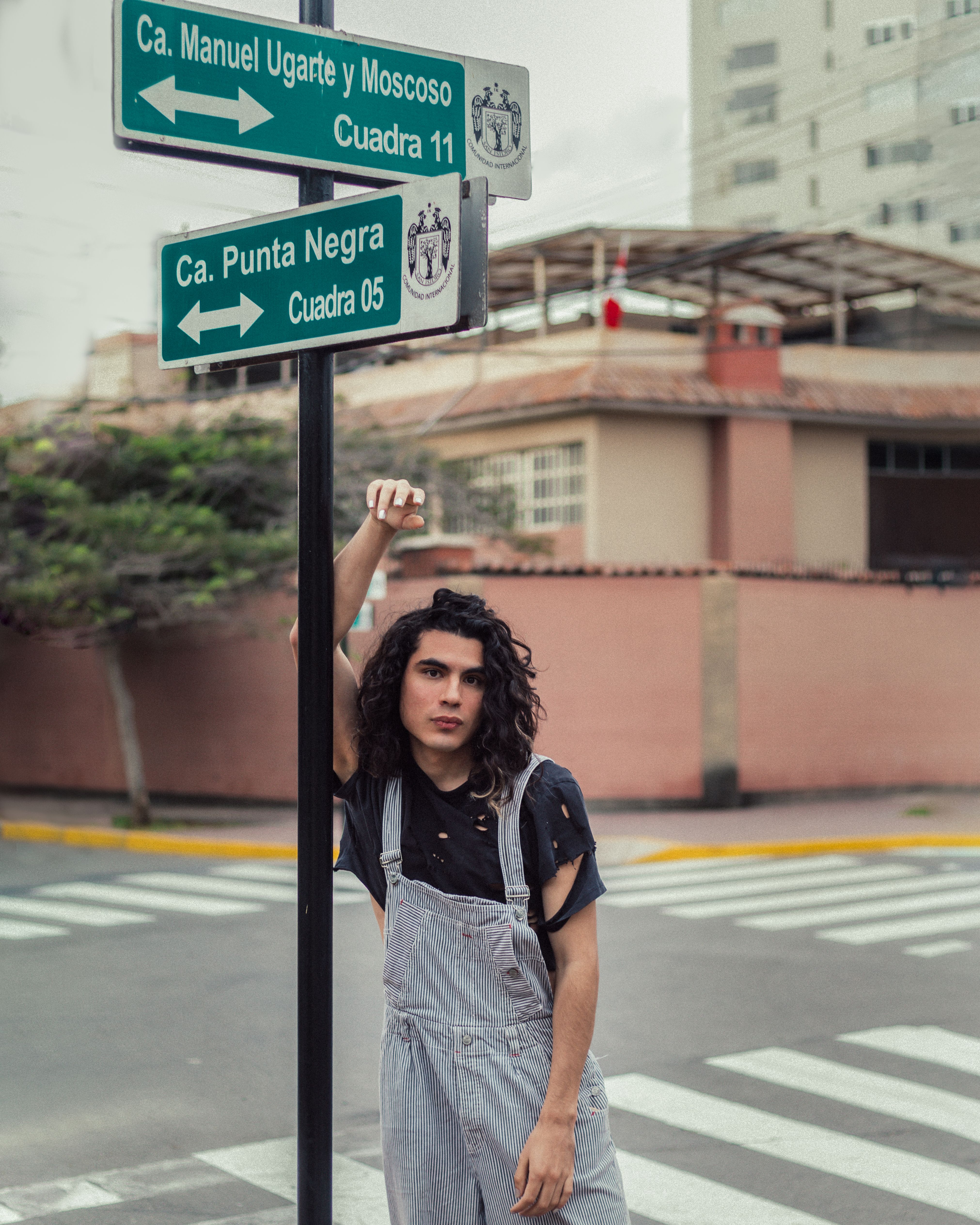 A young adult poses next to street signs in a city setting for an urban vibe.