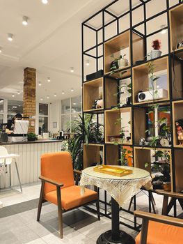 Warm and inviting modern cafe interior featuring vibrant orange seating and decorative shelving.