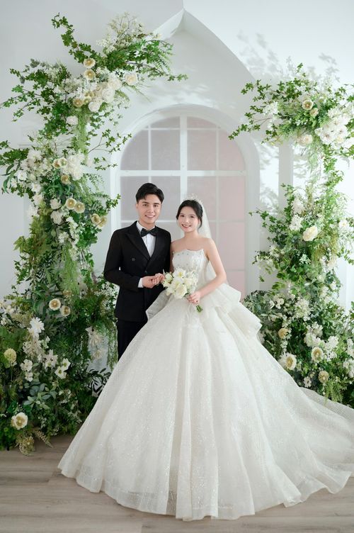 Free Bride and groom in elegant attire posing with lush floral decorations. Stock Photo