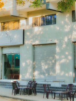 Outdoor seating area at an empty restaurant with closed shutters.