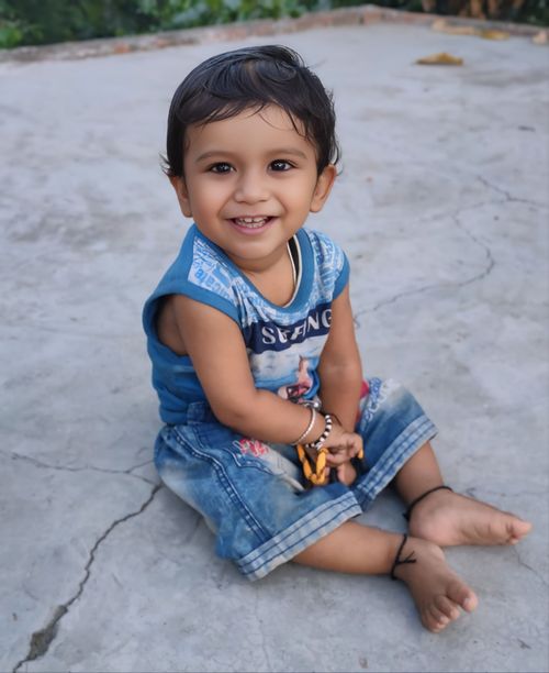 Free A happy baby boy sitting outdoors in casual clothes, smiling brightly on a sunny day. Stock Photo