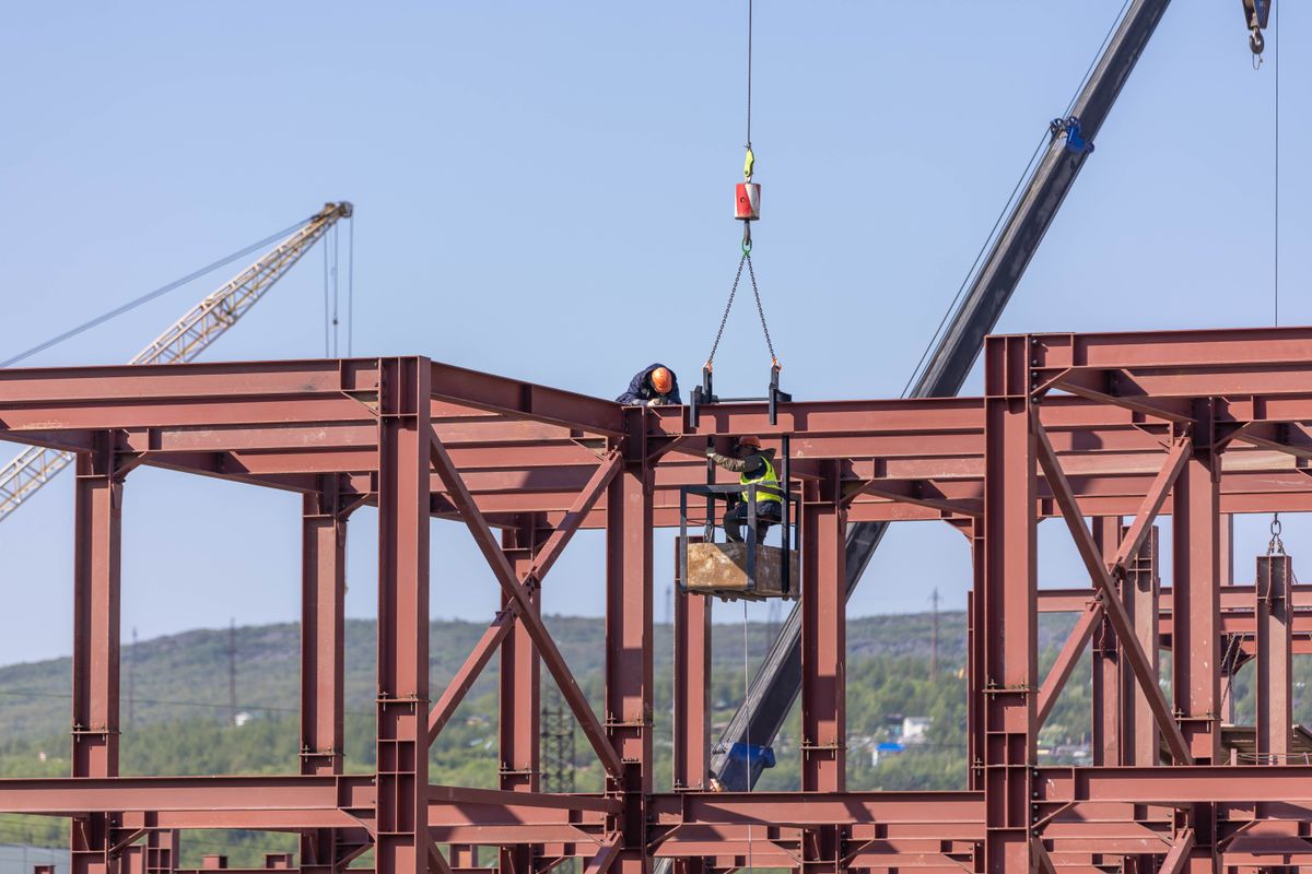 Steel building frame being erected by crane