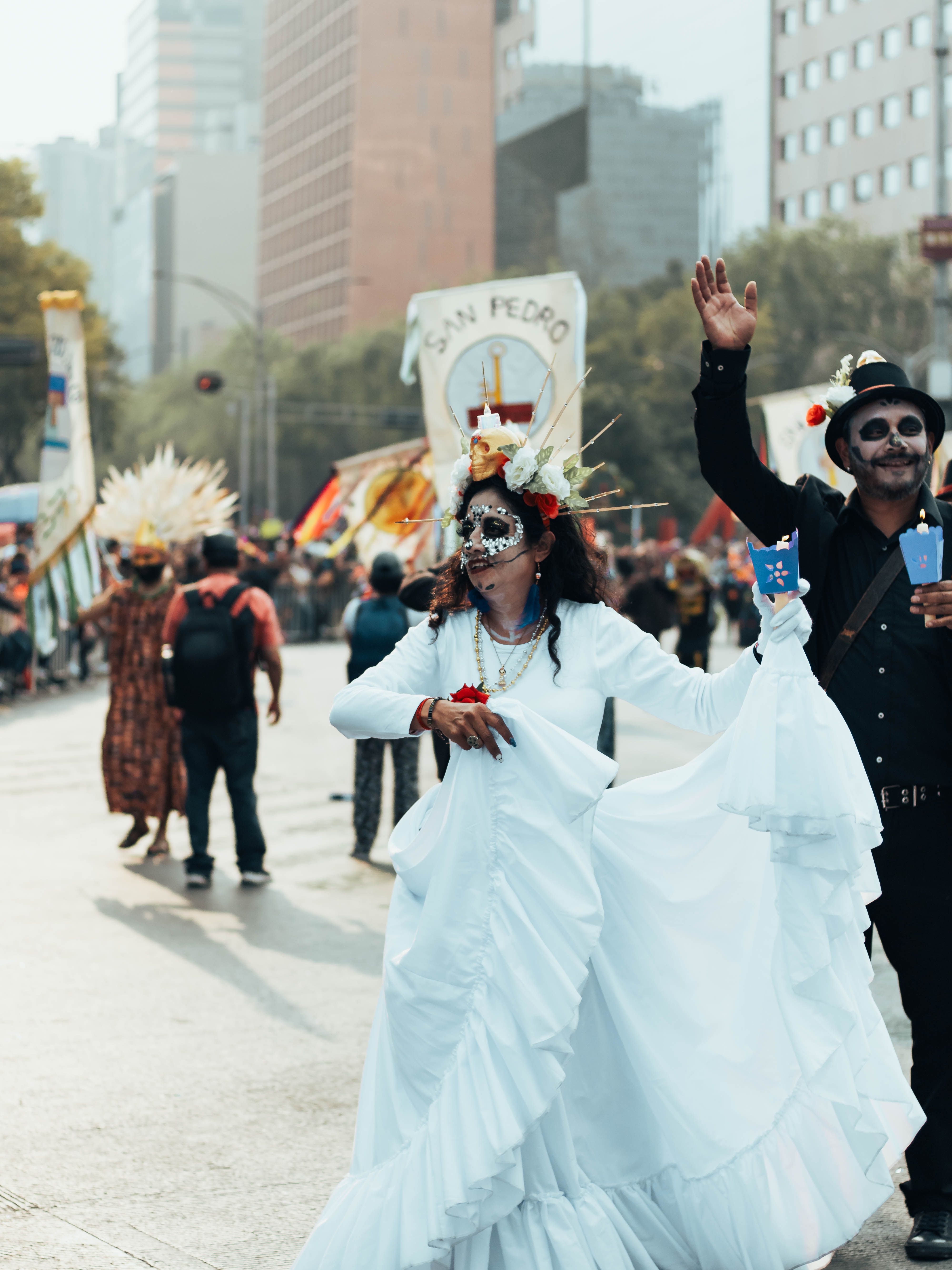 Vibrant Day of the Dead parade in Mexico City's bustling streets with lively participants.