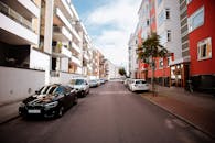 现代城市街道旁，停着汽车，矗立着现代住宅楼