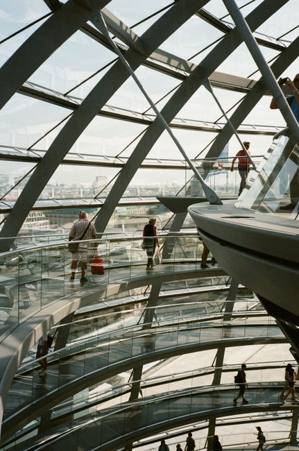 Fotomural Vista interior de una estructura futurista de cúpula de vidrio con personas caminando por caminos en espiral.