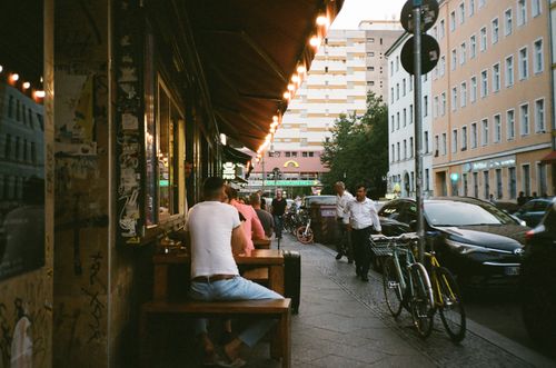 Free A lively urban street scene with people, bicycles, and cafes at twilight, capturing city life. Stock Photo