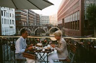 一对夫妇在一家户外餐厅享用晚餐，那里可以俯瞰风景优美的运河和城市建筑