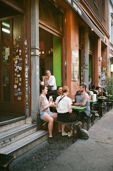 Group of friends enjoying a meal at an outdoor cafe on a city sidewalk.
