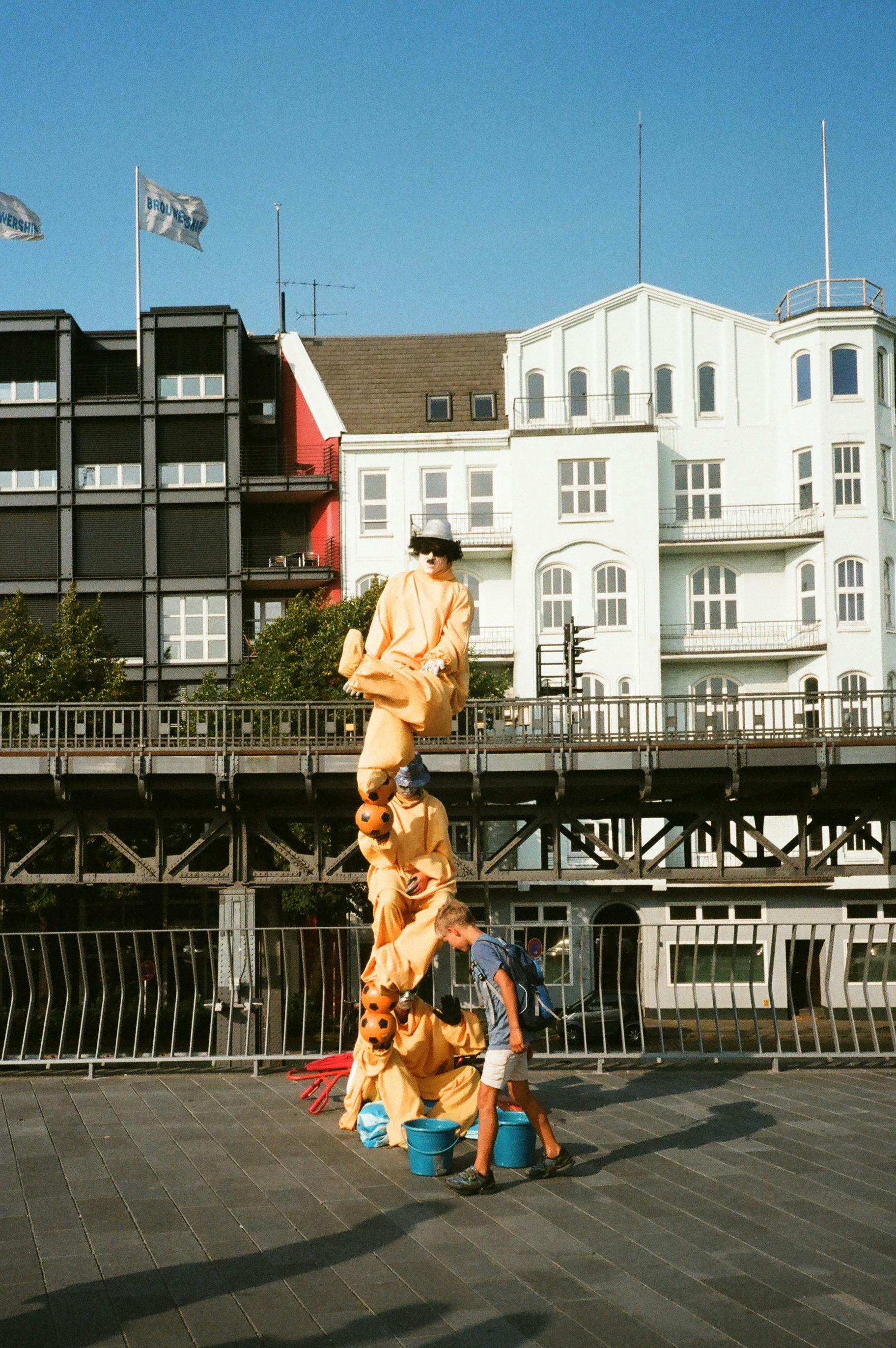 一个孩子注意到，在拥有历史建筑的城市环境中，一位穿着盛装的街头表演者正在表演