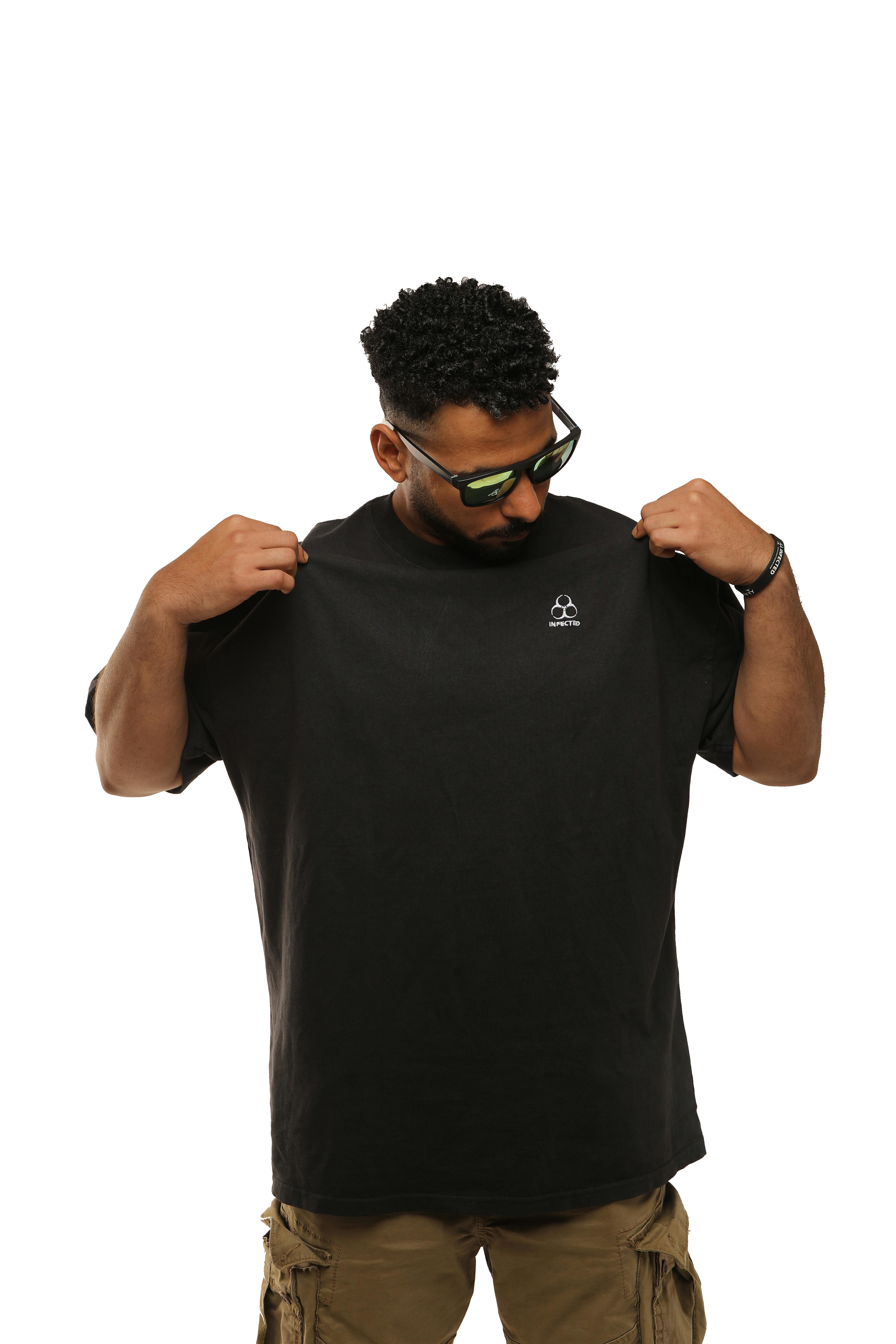 Ücretsiz Siyah tişört ve güneş gözlüğü takan genç adam, stüdyo ortamında gömleğini inceliyor. Stok Fotoğraflar