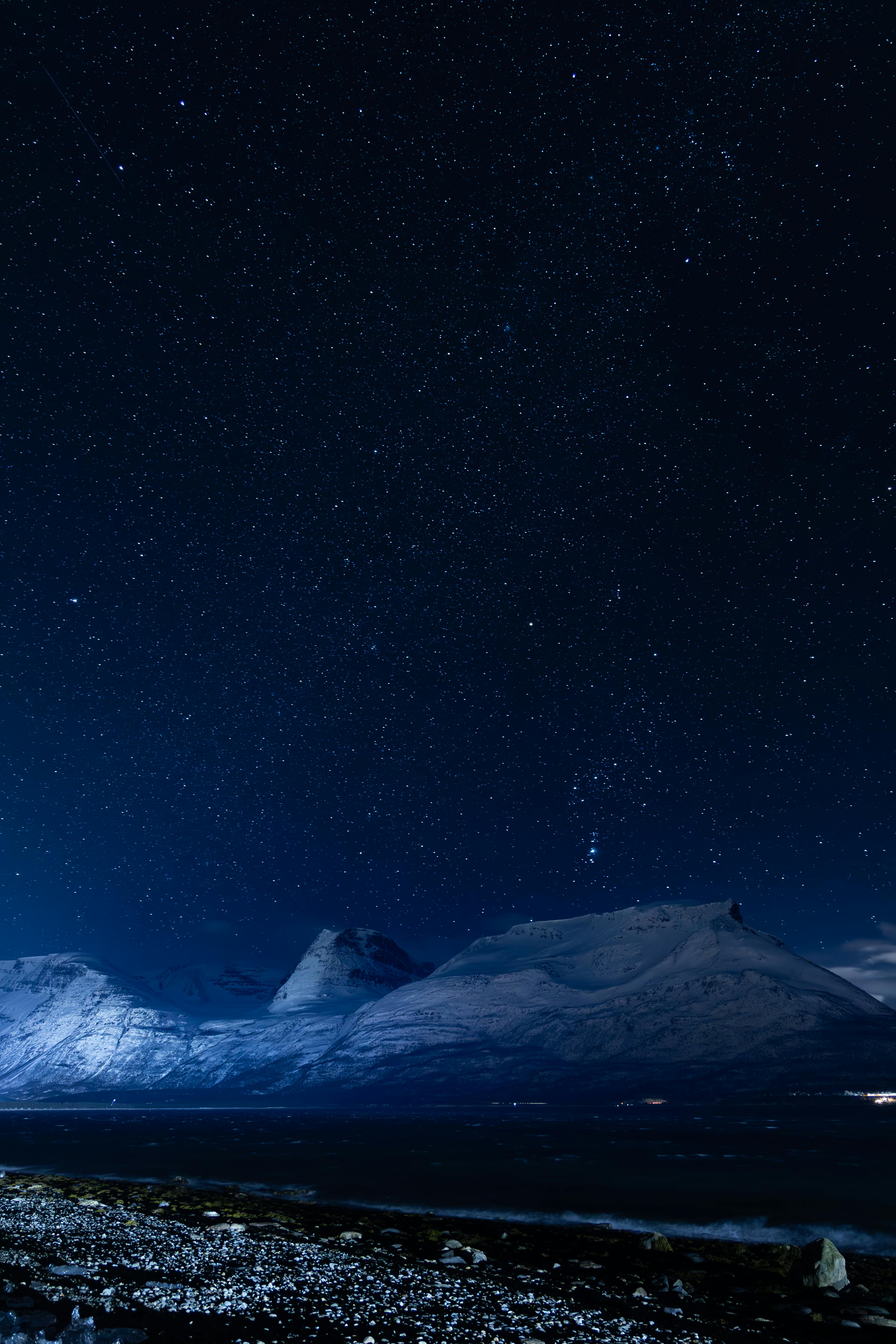 Breathtaking starry sky over snowy mountains in Tromsø, Norway.