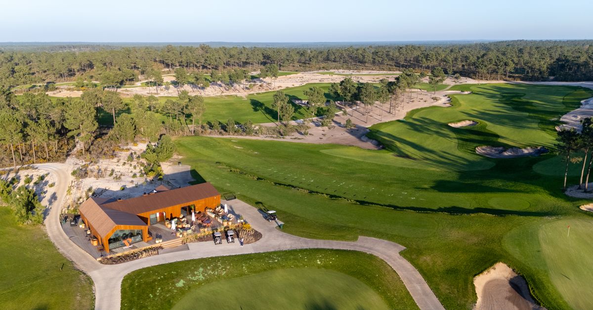 Aerial shot of a golf course with clubhouse in Setúbal, Portugal, surrounded by lush greenery.