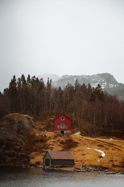 A picturesque red cabin in a tranquil Norwegian landscape near Bergen.