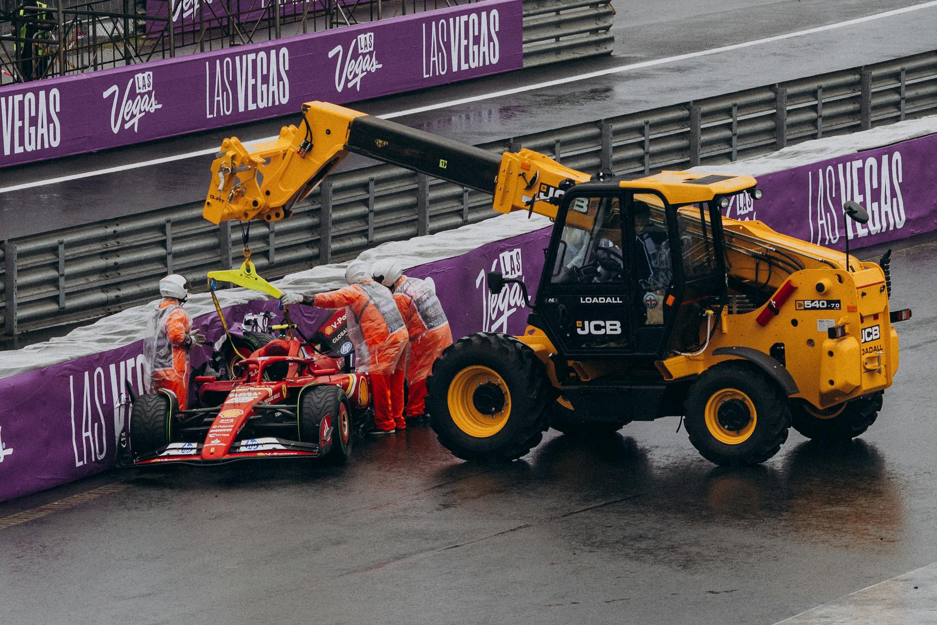 Formula 1 team recovering a race car with a crane at the Las Vegas circuit under rainy conditions.