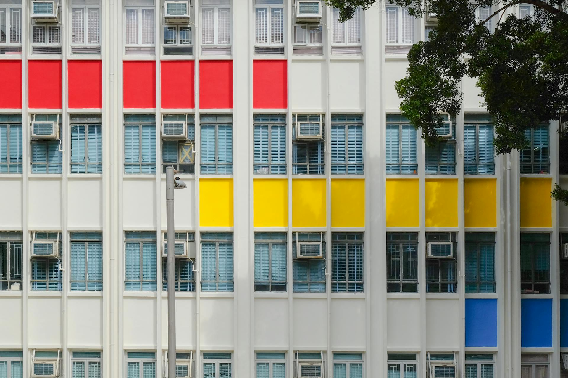 Colorful facade with air conditioning units and geometric patterns, city building.