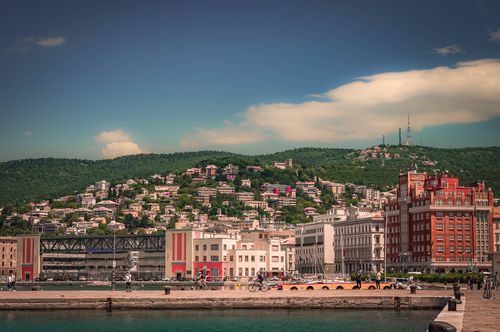Free Lively coastal cityscape featuring vibrant buildings and lush hills under a bright sky. Stock Photo