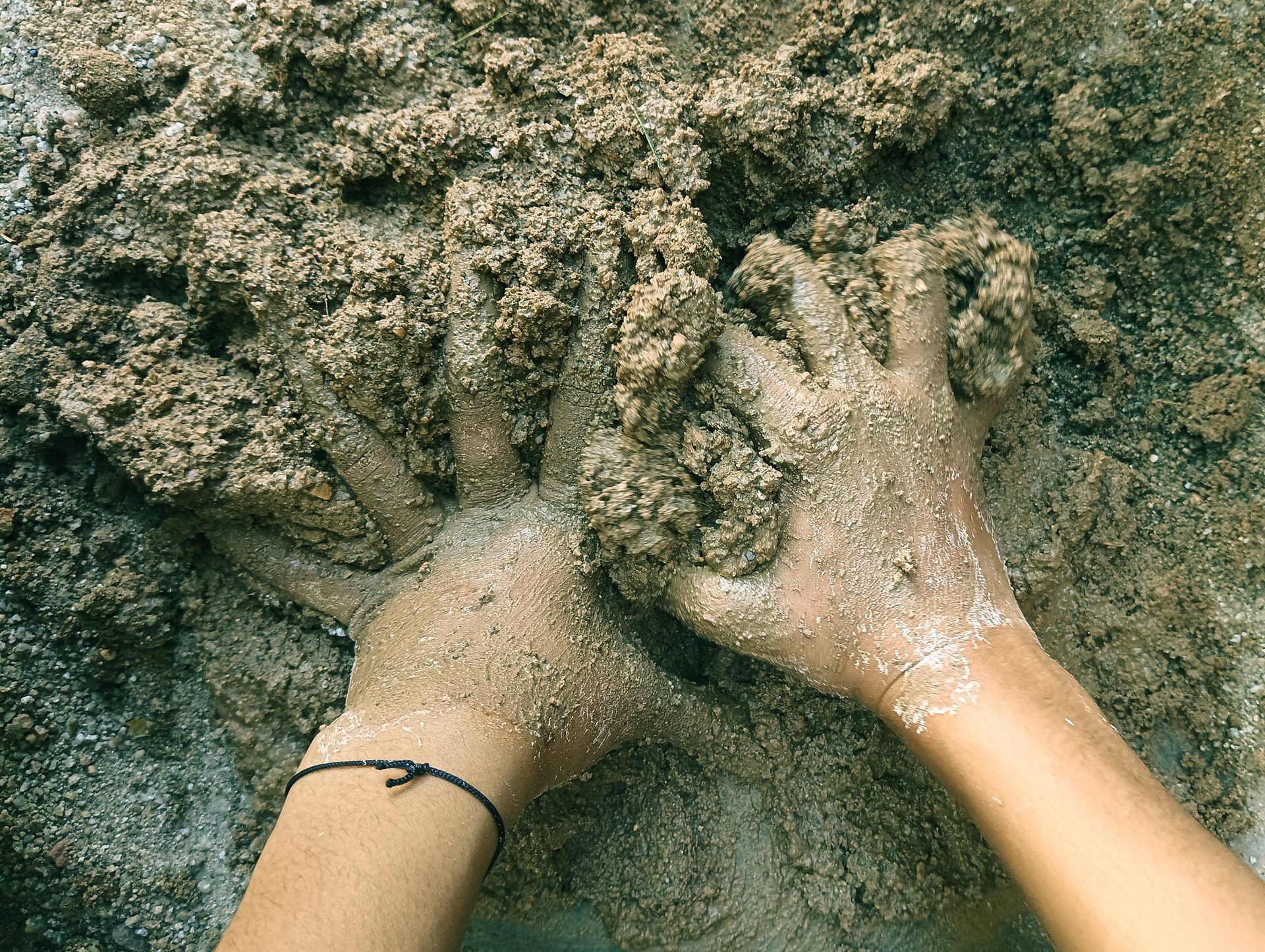 Close-up of hands kneading clay and mud, showcasing earthy art and handmade creativity.