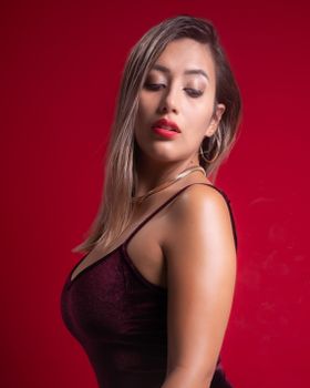 Portrait of a woman in a red dress, exuding elegance and confidence against a red background.