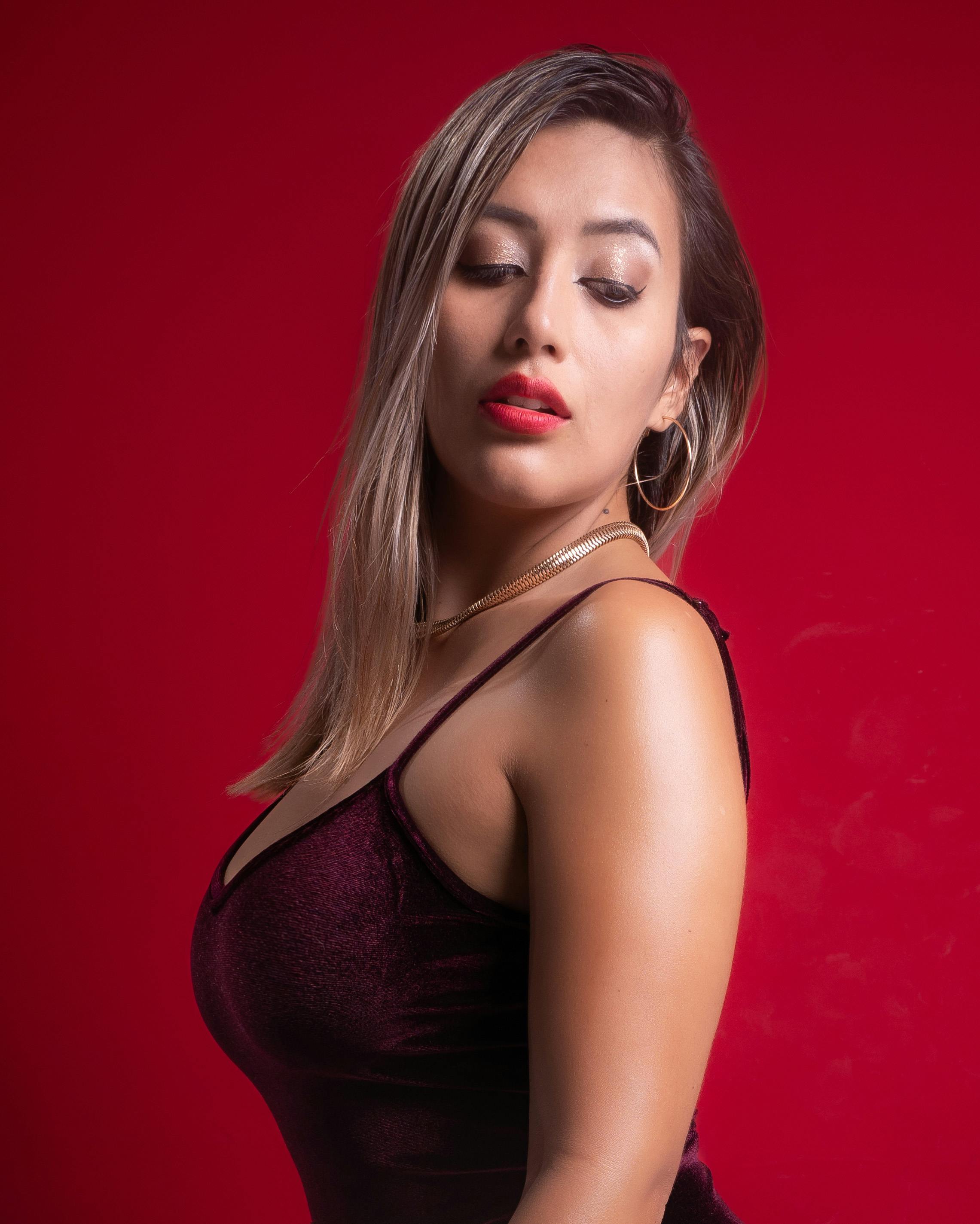 bezplatná Portrét ženy v červených šatech vyzařující eleganci a sebevědomí na červeném pozadí. Základová fotografie