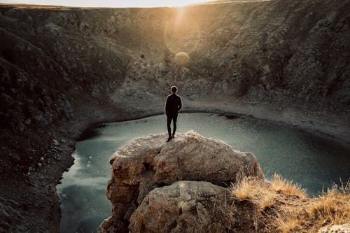 Man Overlooking a Lake from a Cliff