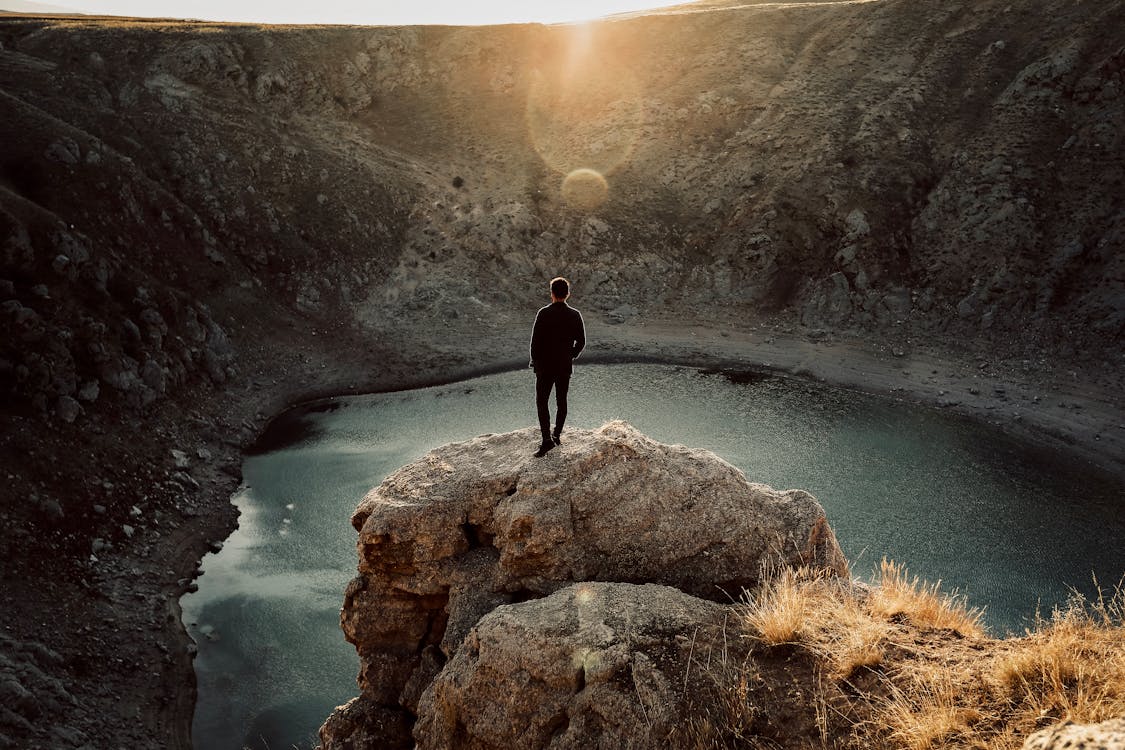 Man Overlooking a Lake from a Cliff