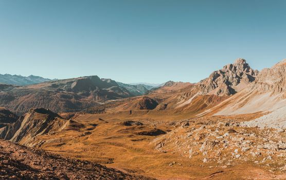 Breathtaking view of rugged mountains with autumn foliage under a clear blue sky.