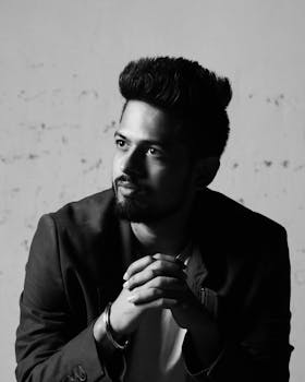 一张黑白肖像，画中是一位表情若有所思、胡须浓密的年轻人