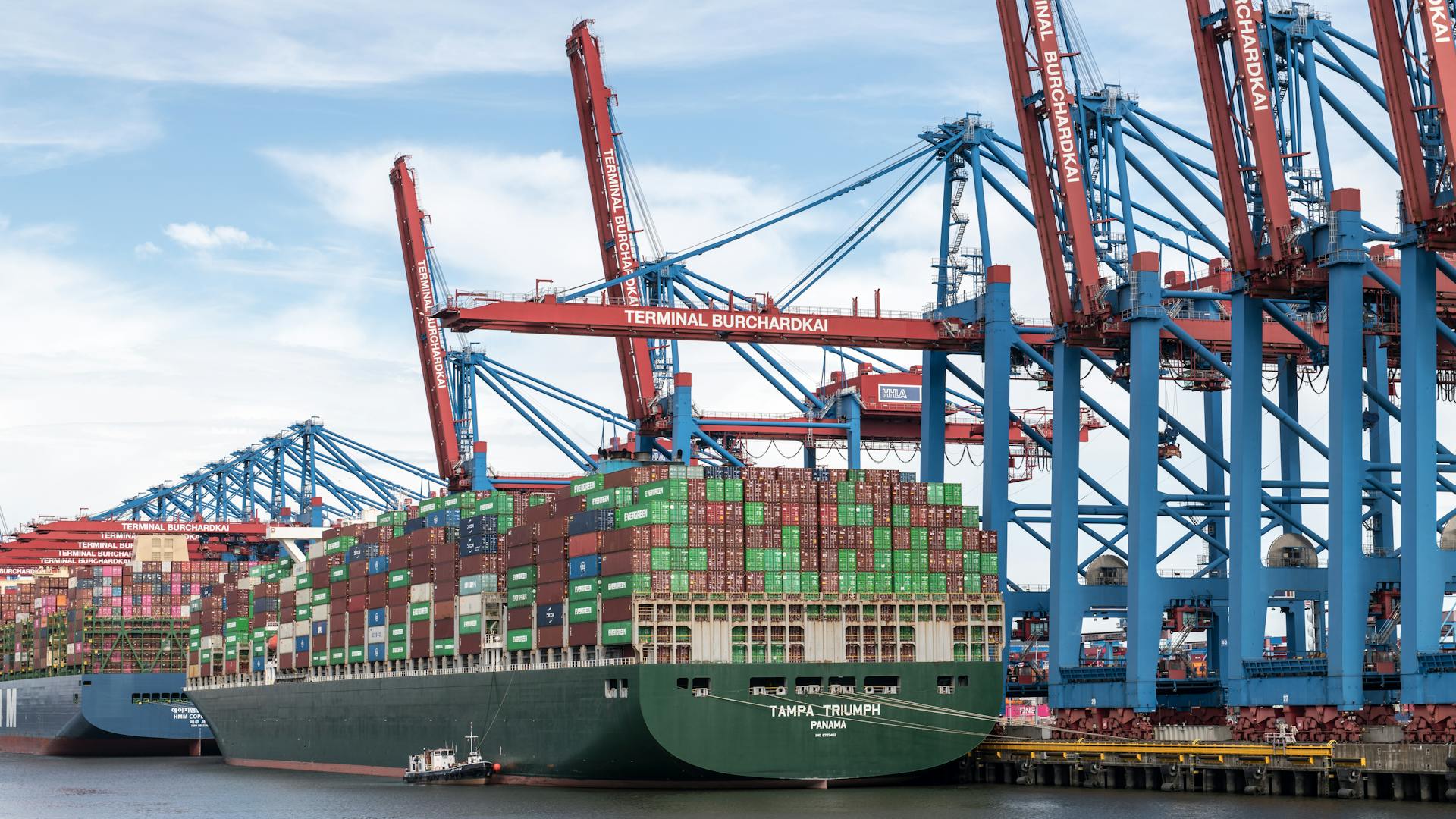 A massive container ship docked at Terminal Burchardkai in Hamburg port, showcasing cargo handling.