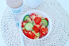 Bright vegan salad with quinoa, cucumbers, and tomatoes in a cozy home setting.