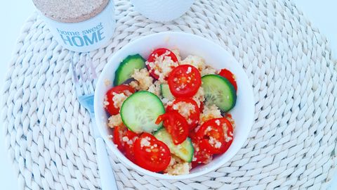 Bright vegan salad with quinoa, cucumbers, and tomatoes in a cozy home setting.