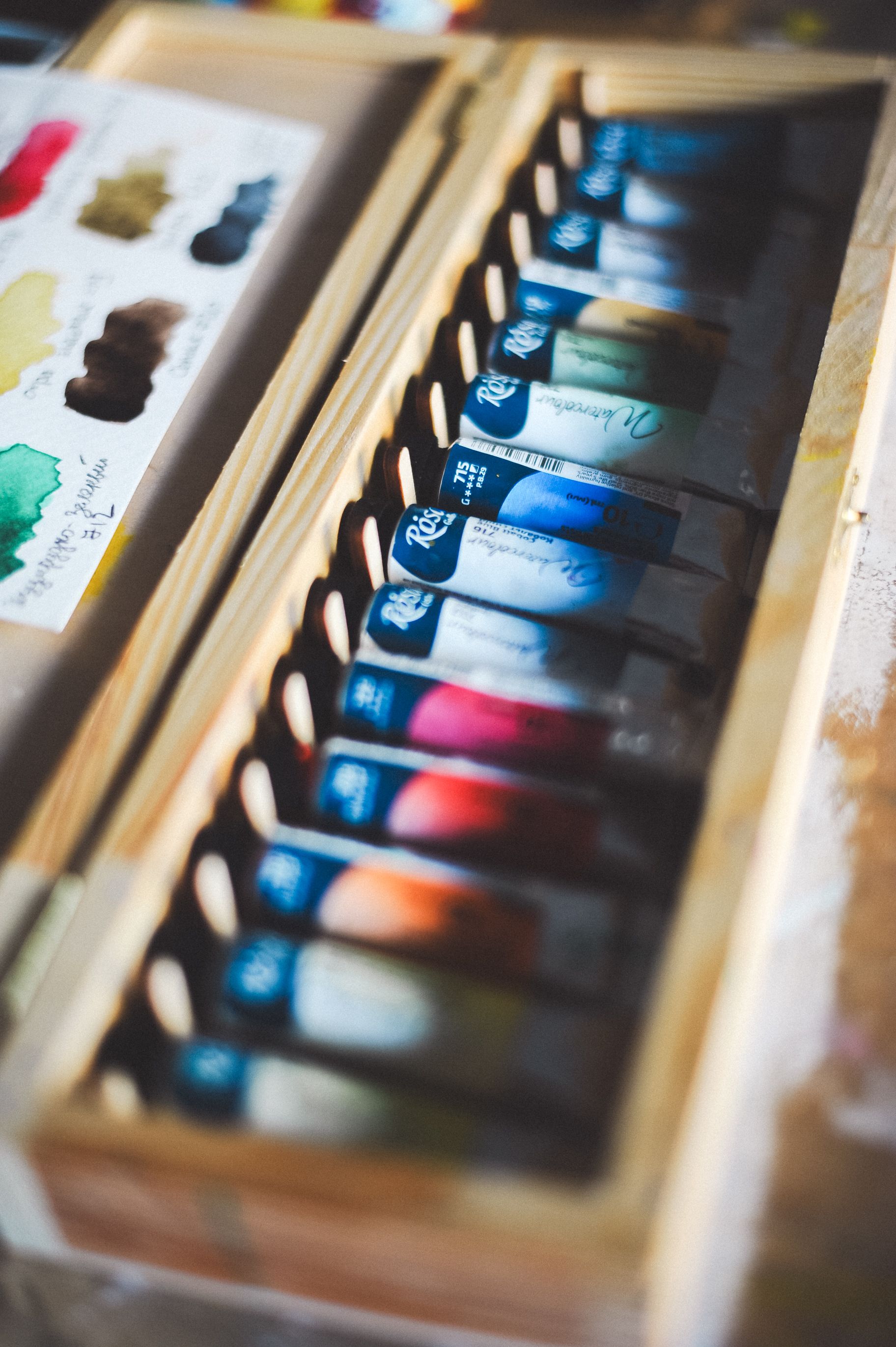 A long row of paint tubes in a wooden box
